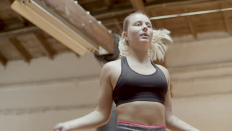 Medium-shot-of-focused-woman-jumping-rope-in-gym